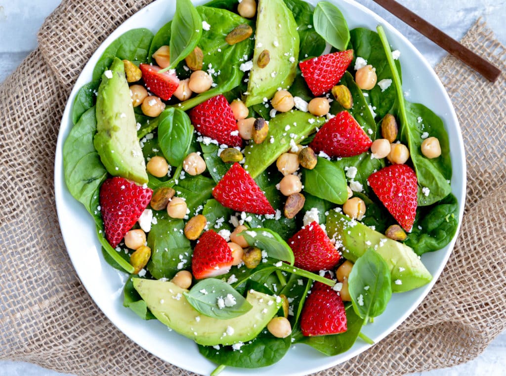 strawberry and basil salad with chickpeas, cheese and nuts on a white plate